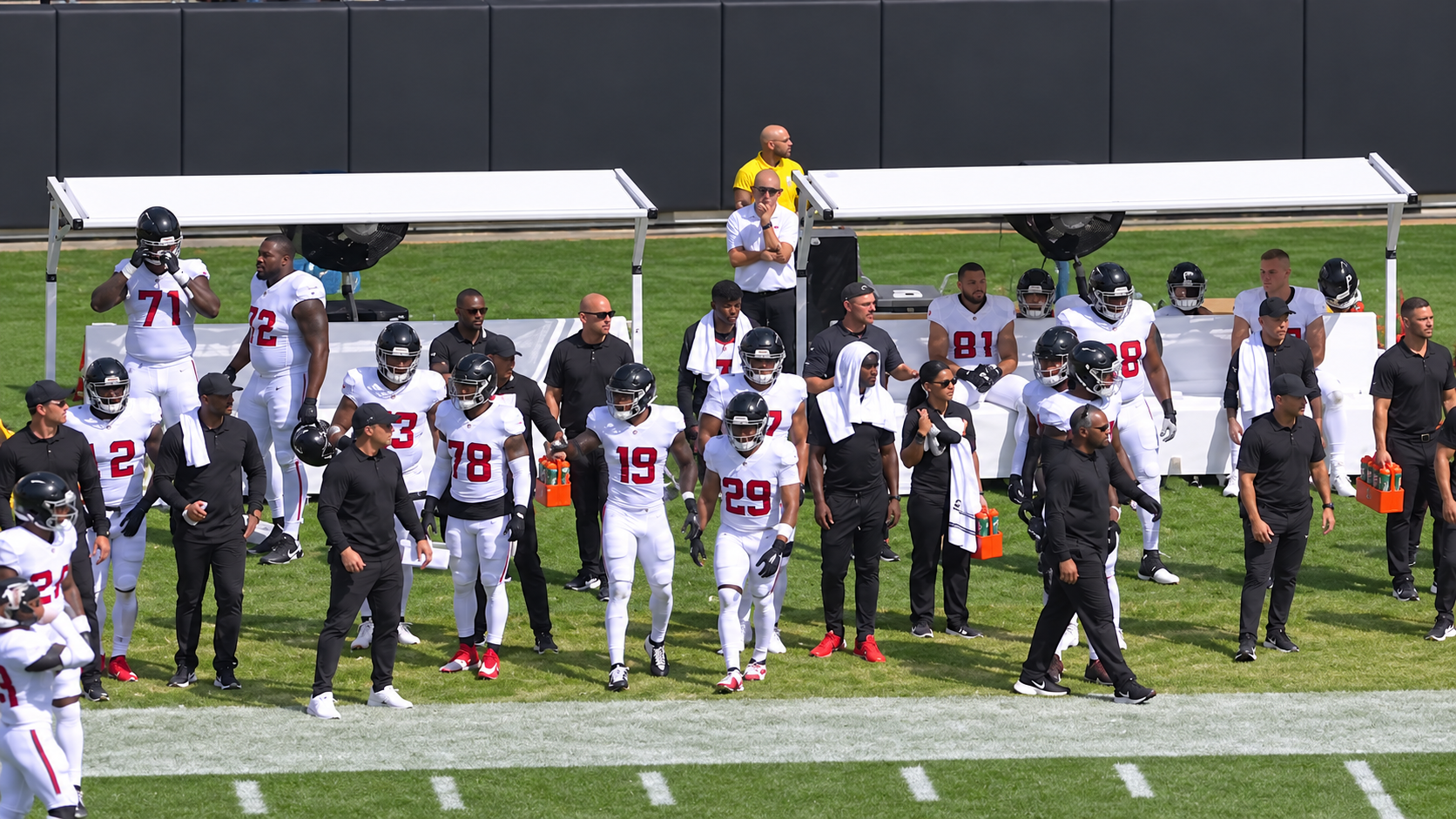 Podium Shades shade systems covering players and staff on a professional football sideline during warmups