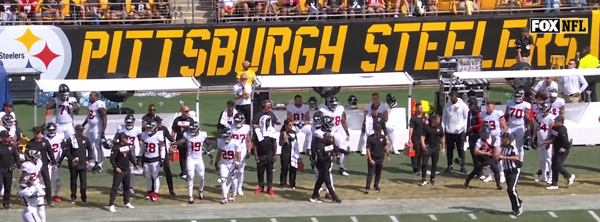 Two Podium Shades portable sideline shade systems covering staff and players along an NFL sideline
